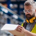 Safety inspector reviewing documentation on a clipboard inside an industrial facility